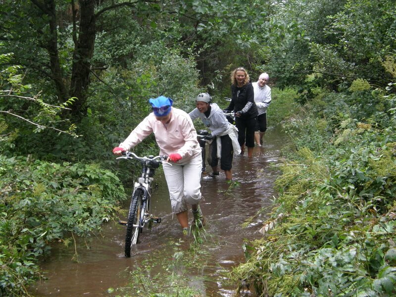 Rattamatkajad lükkamas jalgrattaid mööda üleujutatud metsarada