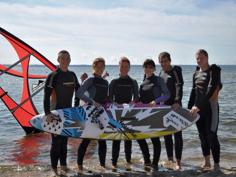 Rõõmsatujulised surfiharrastajad poseerimas värvikireva surfilauaga